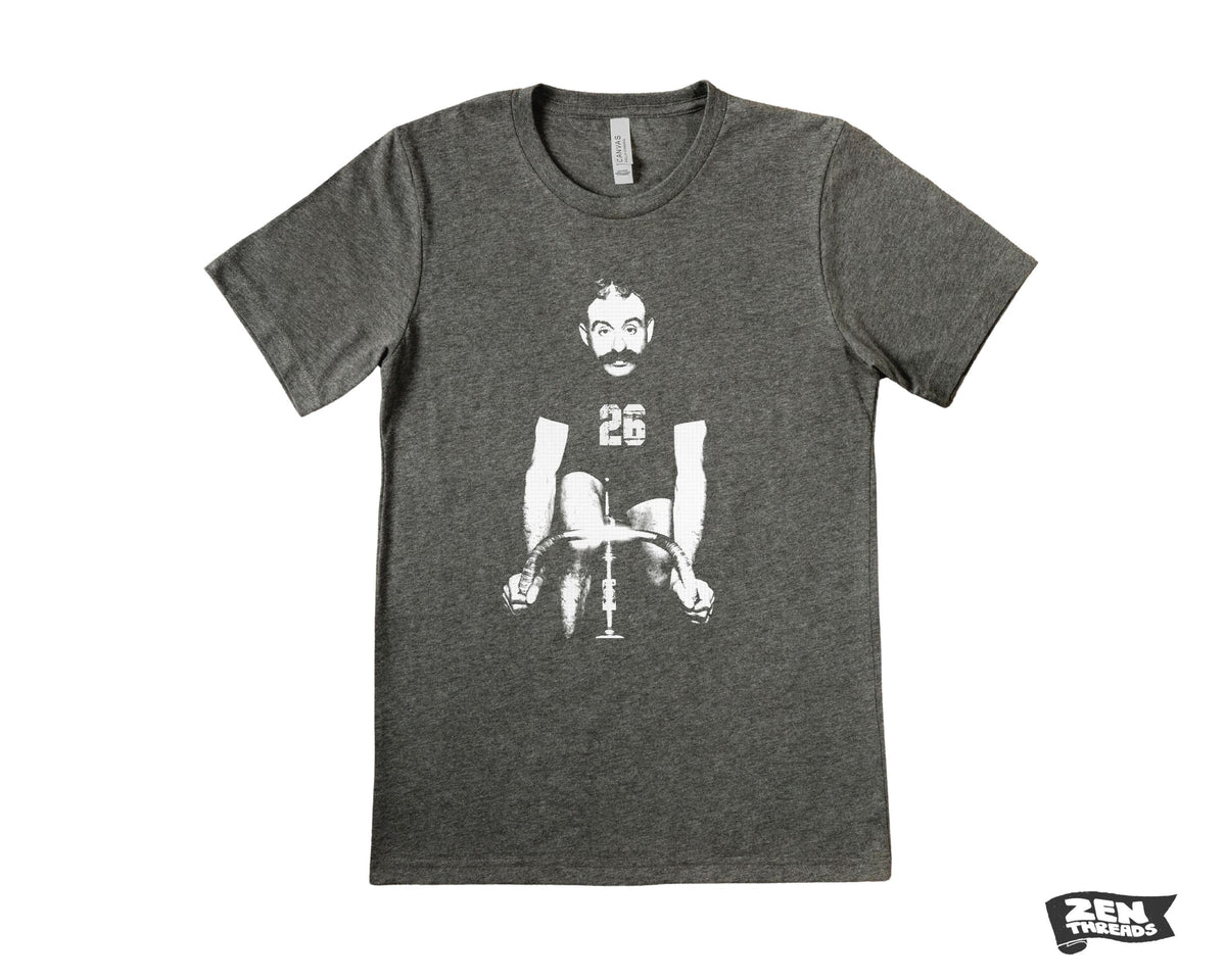 May include: A gray t-shirt with a graphic of a man riding a bicycle. The man has a mustache and is wearing a jersey with the number 26. The t-shirt has a crew neck and short sleeves. The Zen Threads logo is visible in the bottom right corner.